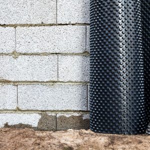 A roll of drainage board for exterior waterproofing resting on a wall