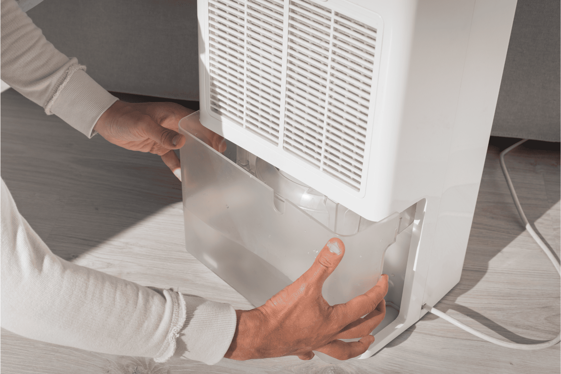 someone removing the water bucket on a dehumidifier