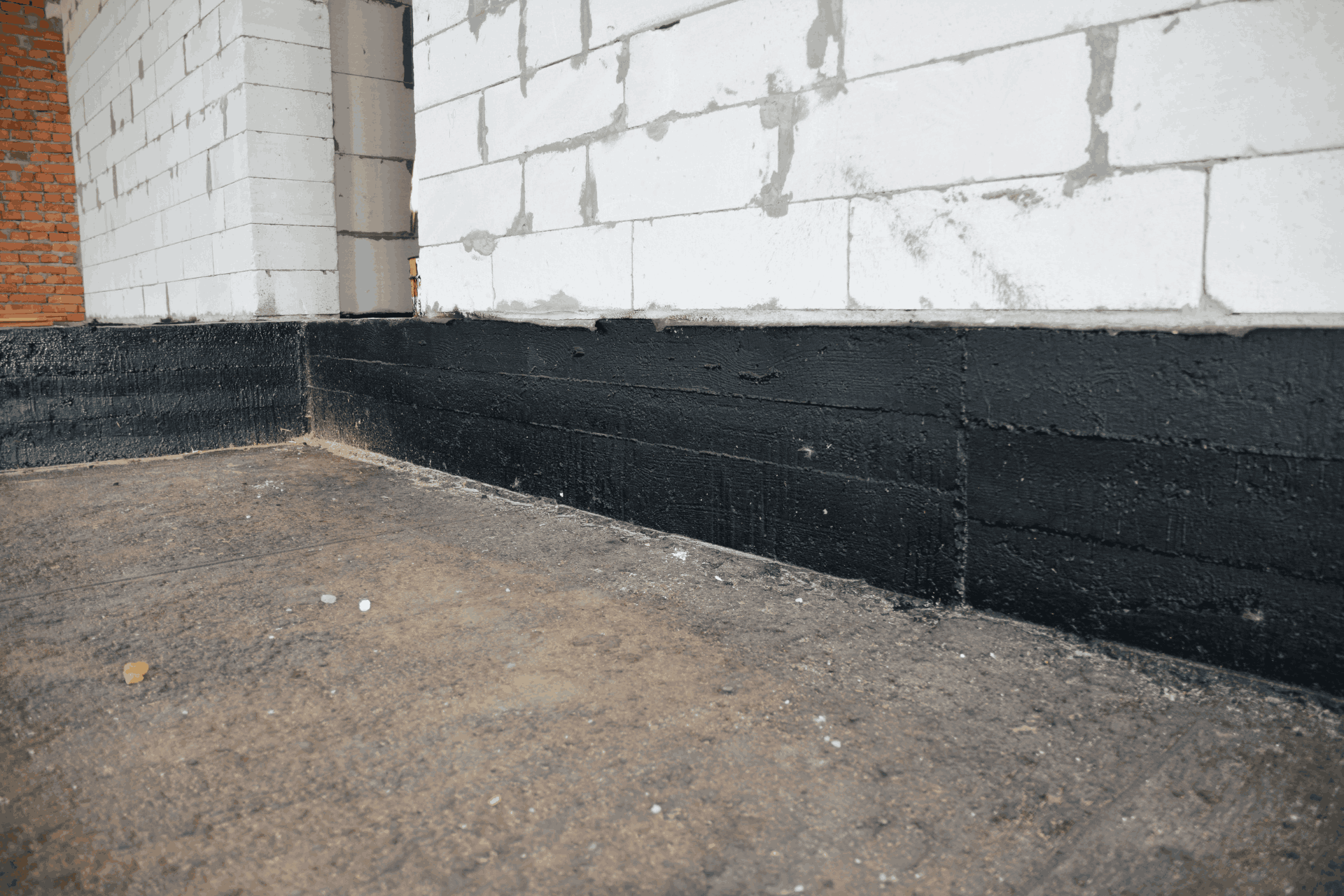 Black waterproofing that has been applied to a basement wall